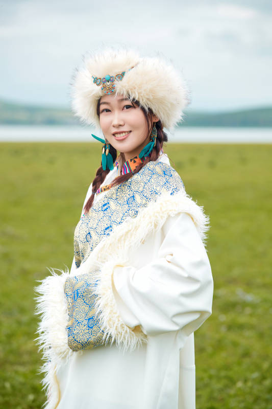 穿白色藏族服饰在草原拍照的少女