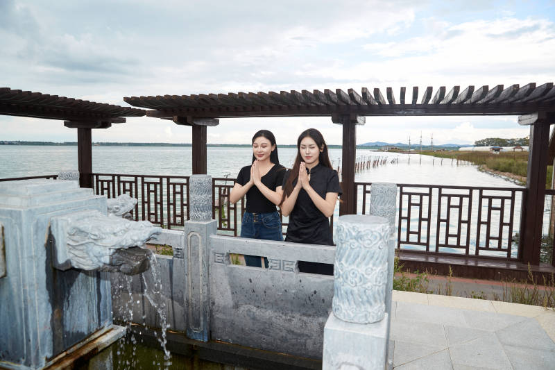 盛夏在景区湖边许愿井祈福的美女