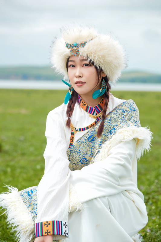 穿白色藏族服饰在草原拍照的少女