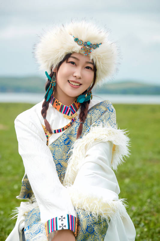 穿白色藏族服饰在草原拍照的少女