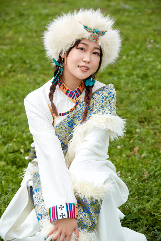 穿白色藏族服饰在草原拍照的少女