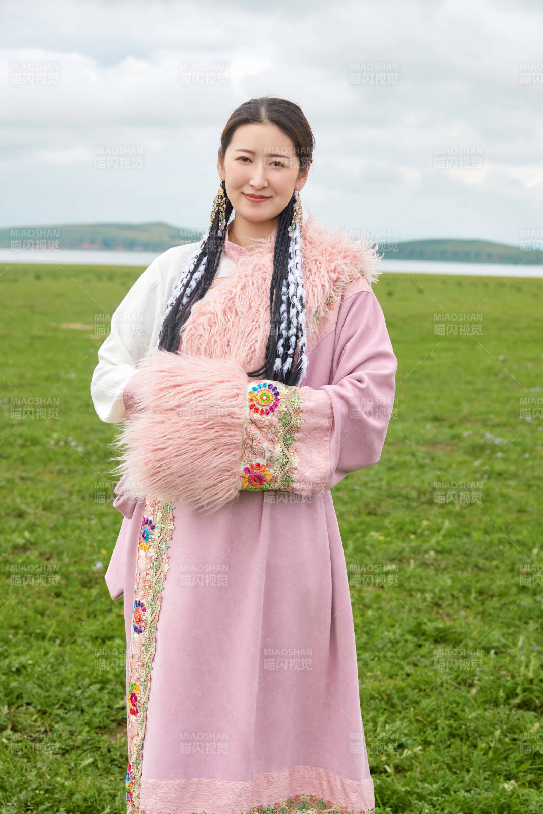 身穿粉色藏族服饰在草原拍照的少女