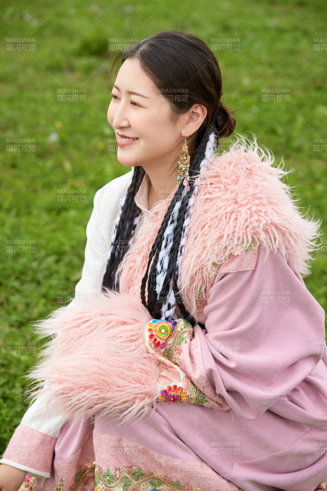 身穿粉色藏族服飾在草原拍照的少女