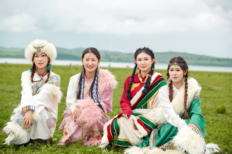 穿藏族服饰在草原拍照游玩的姑娘们
