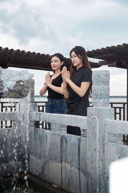 盛夏在景区湖边许愿井祈福的美女