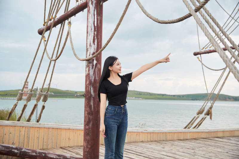 在湖畔木制帆船上拍照游玩的亚洲女性