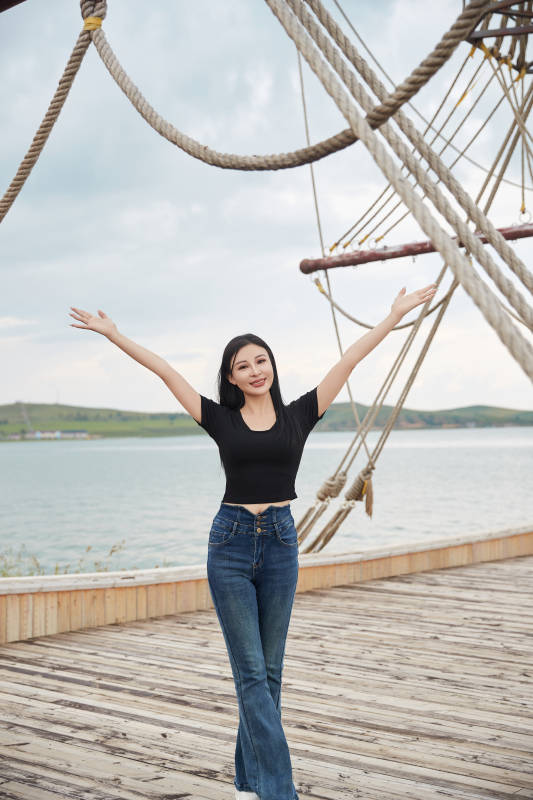 在湖畔木制帆船上拍照游玩的亚洲女性