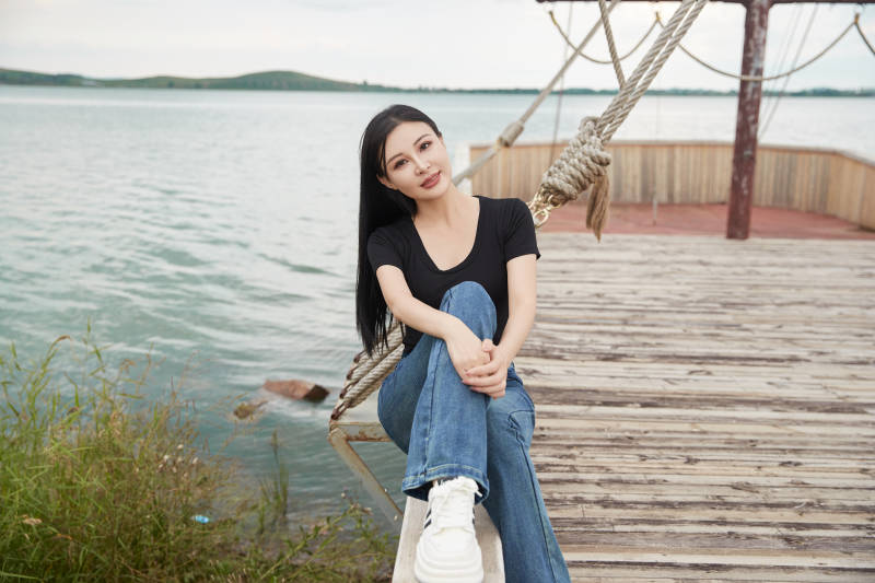 在湖畔木制帆船上拍照游玩的亚洲女性