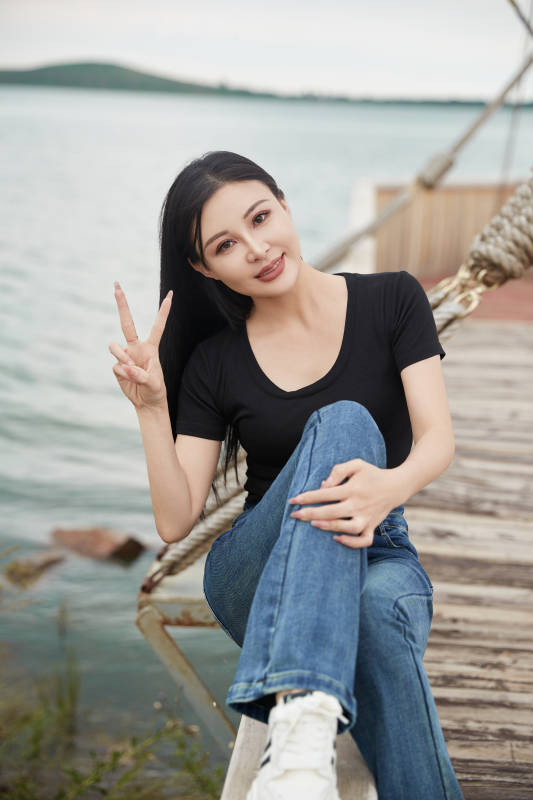 在湖畔木制帆船上拍照游玩的亚洲女性