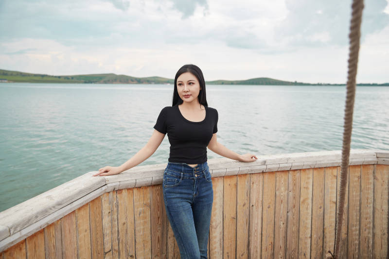 在湖畔木制帆船上拍照游玩的亚洲女性