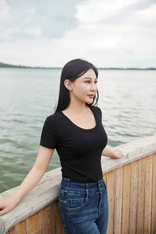 在湖畔木制帆船上拍照游玩的亚洲女性