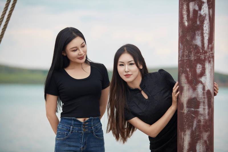 在湖畔木制帆船上拍照游玩的闺蜜