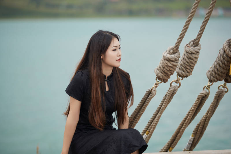 在湖畔木制帆船上拍照游玩的亚洲女性