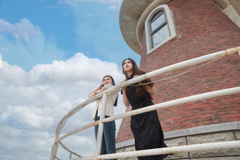 在旅游区湖边打卡点拍照的美女闺蜜