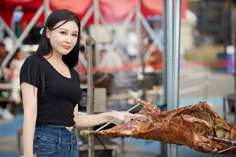 在户外烤全羊自助餐会品尝美食的美女