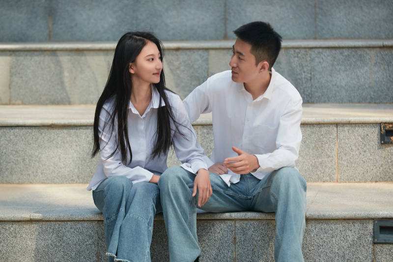 坐在户外台阶上的青年情侣