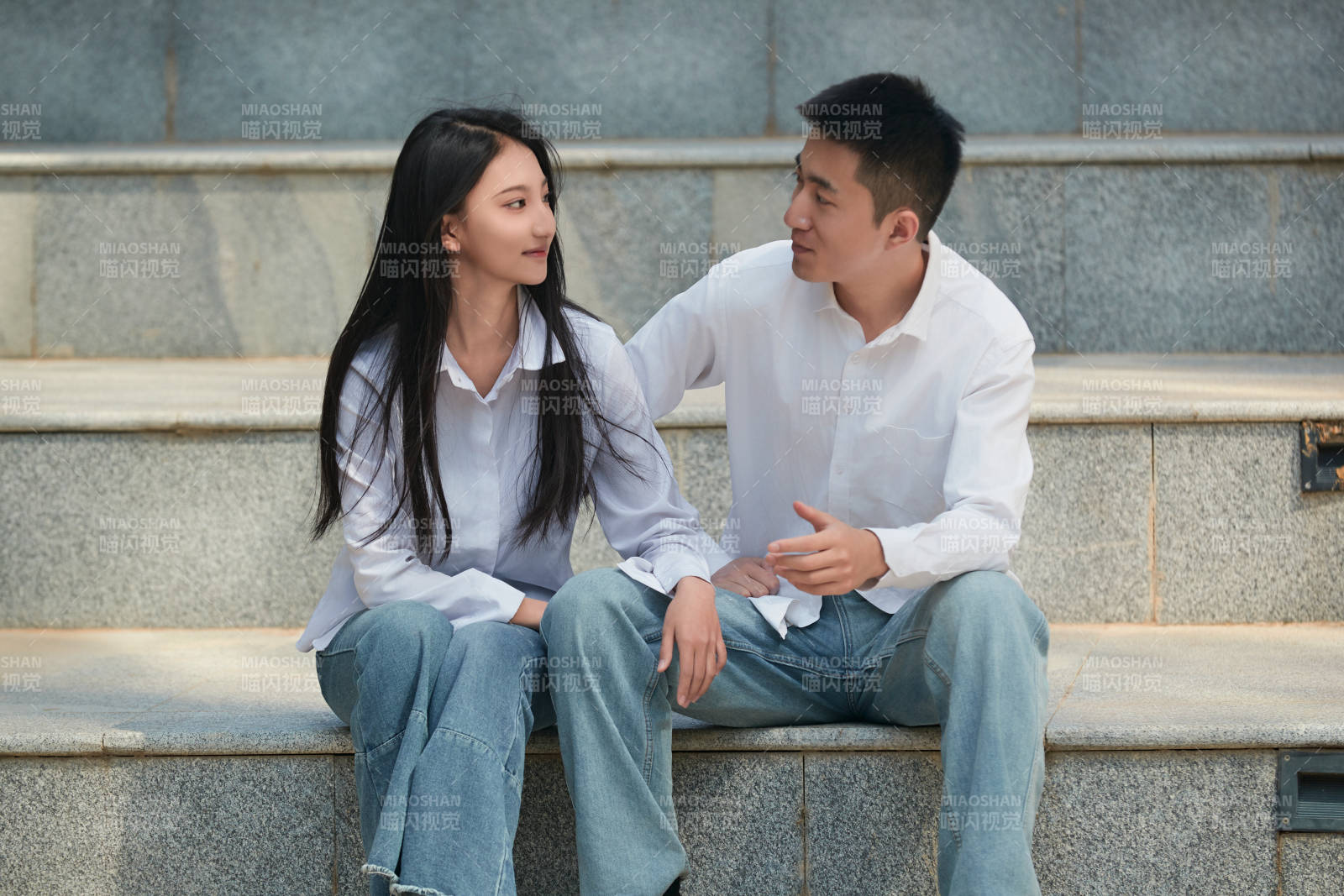 坐在户外台阶上的青年情侣