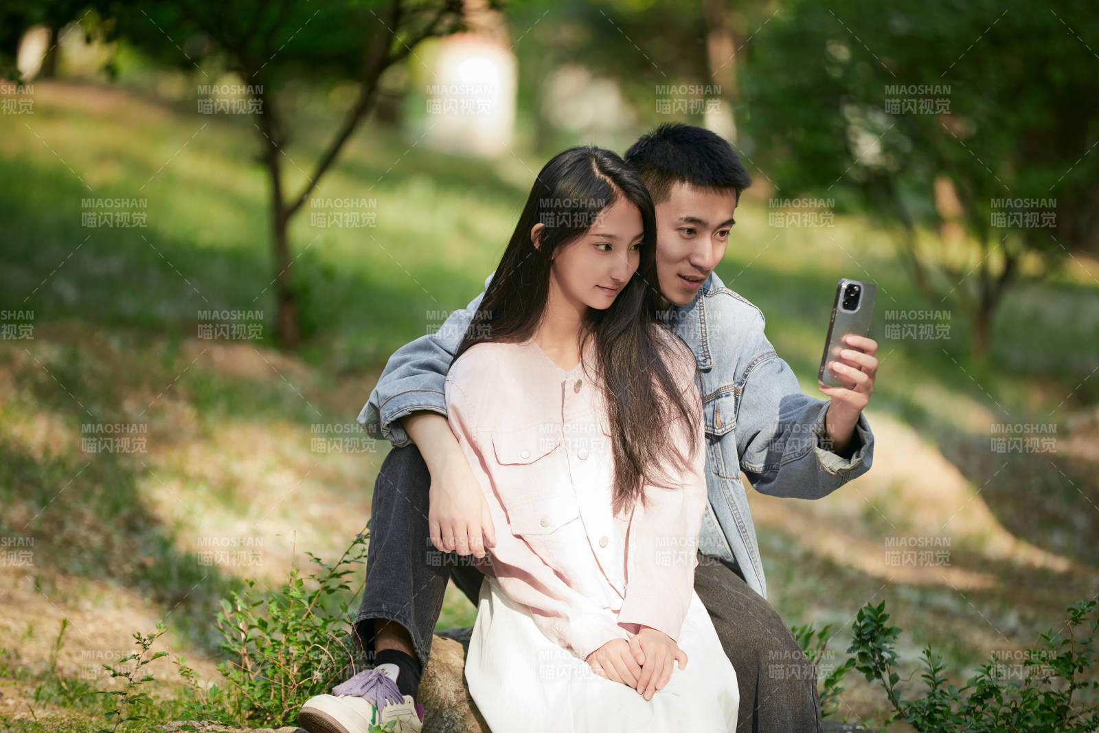 戶外公園里用手機自拍的年輕情侶