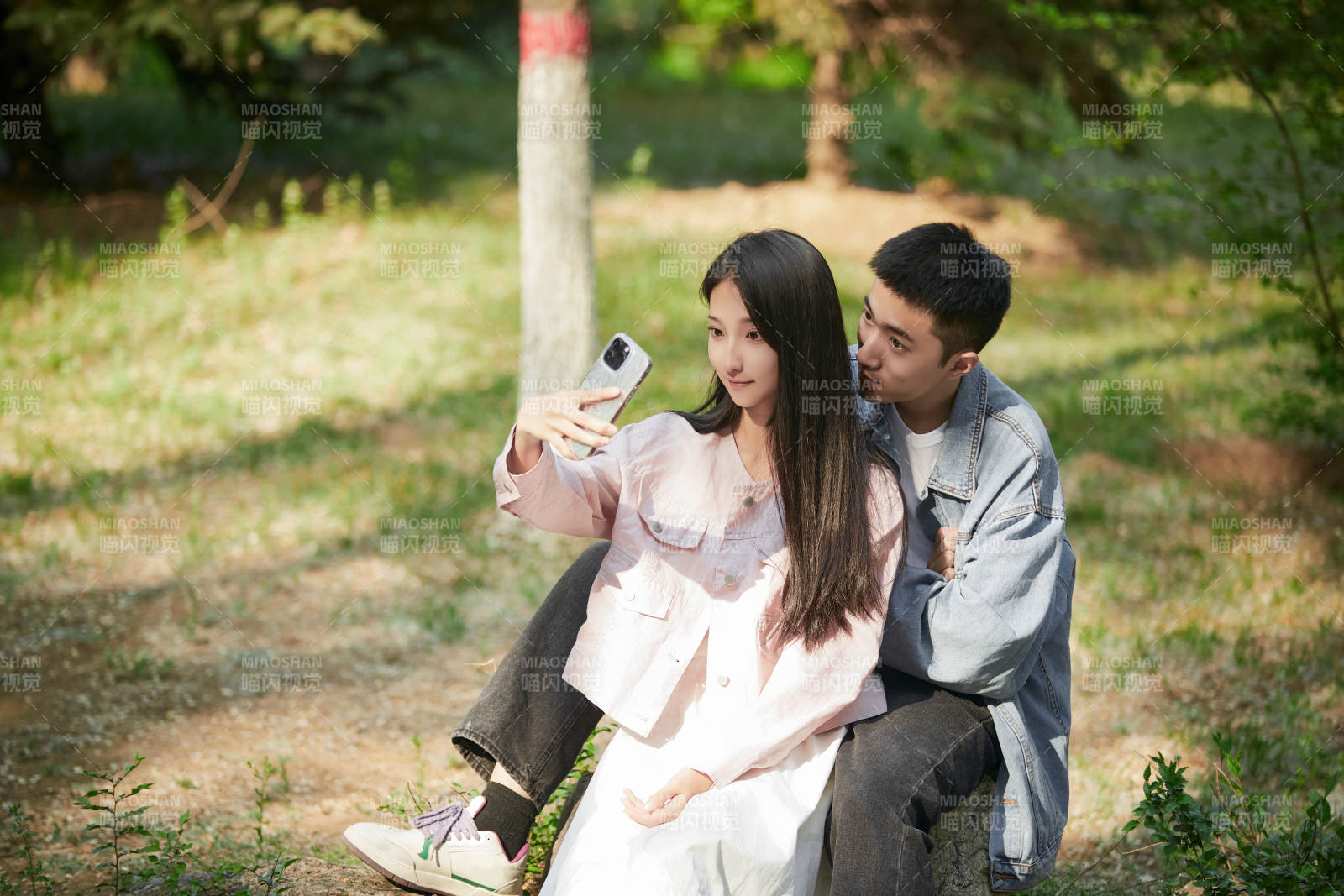 戶外公園里用手機自拍的年輕情侶