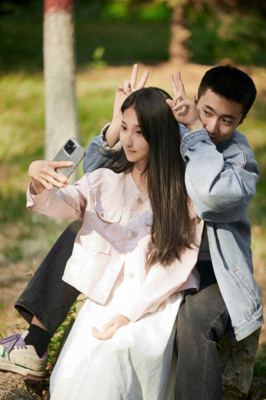 户外公园里用手机自拍的年轻情侣