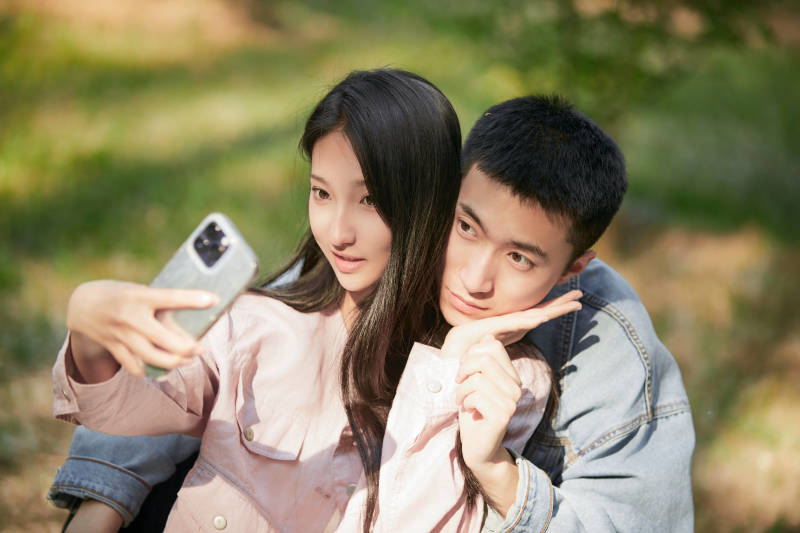 户外公园里用手机自拍的年轻情侣