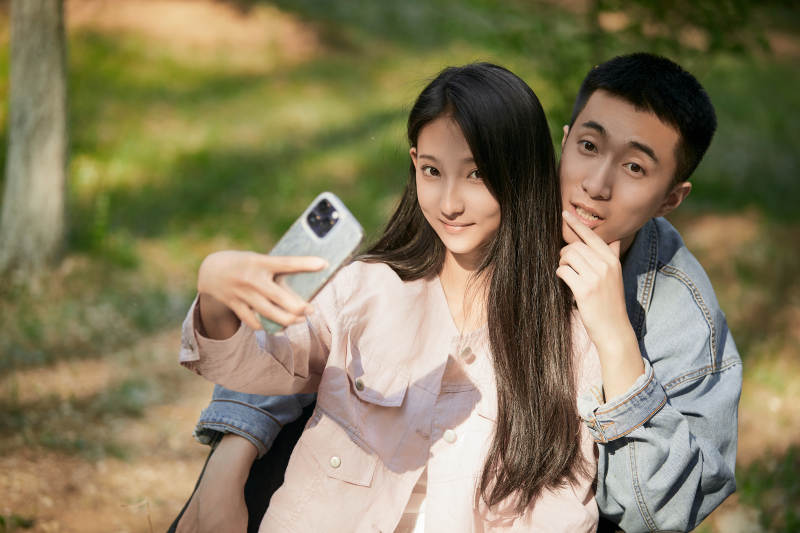 户外公园里用手机自拍的年轻情侣