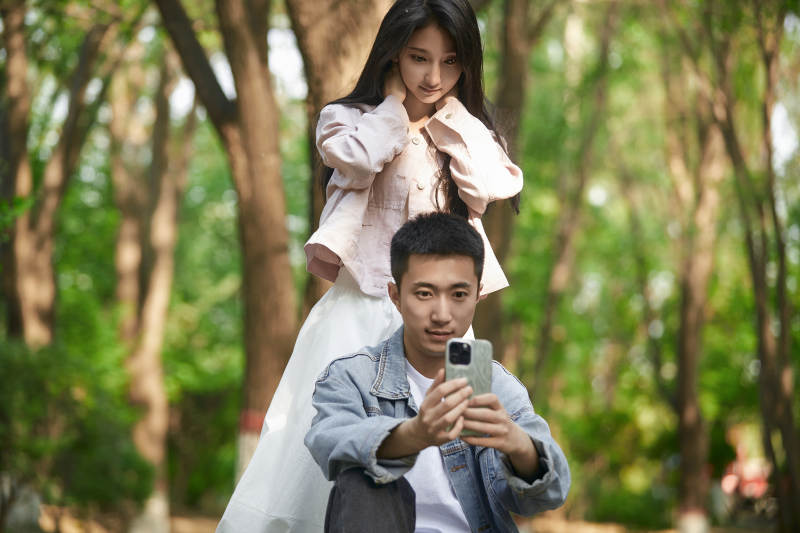 户外公园里用手机自拍的年轻情侣