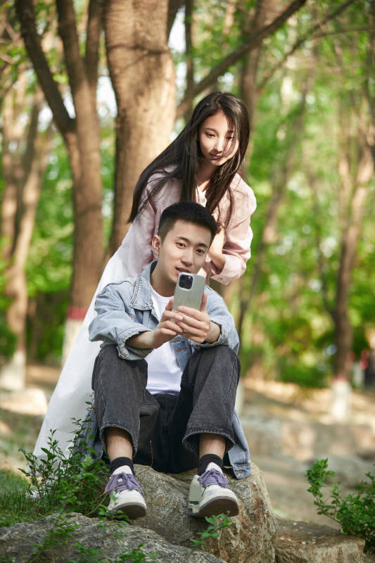 户外公园里用手机自拍的年轻情侣