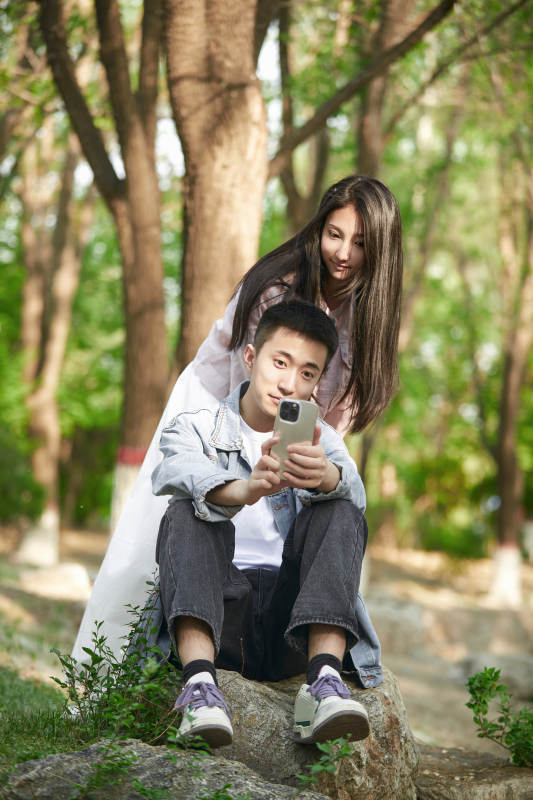 户外公园里用手机自拍的年轻情侣