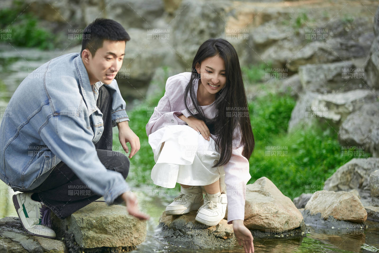 在公园小溪旁嬉戏玩水的青年情侣