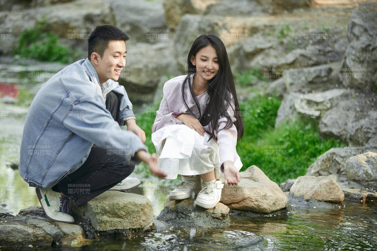 在公园小溪旁嬉戏玩水的青年情侣