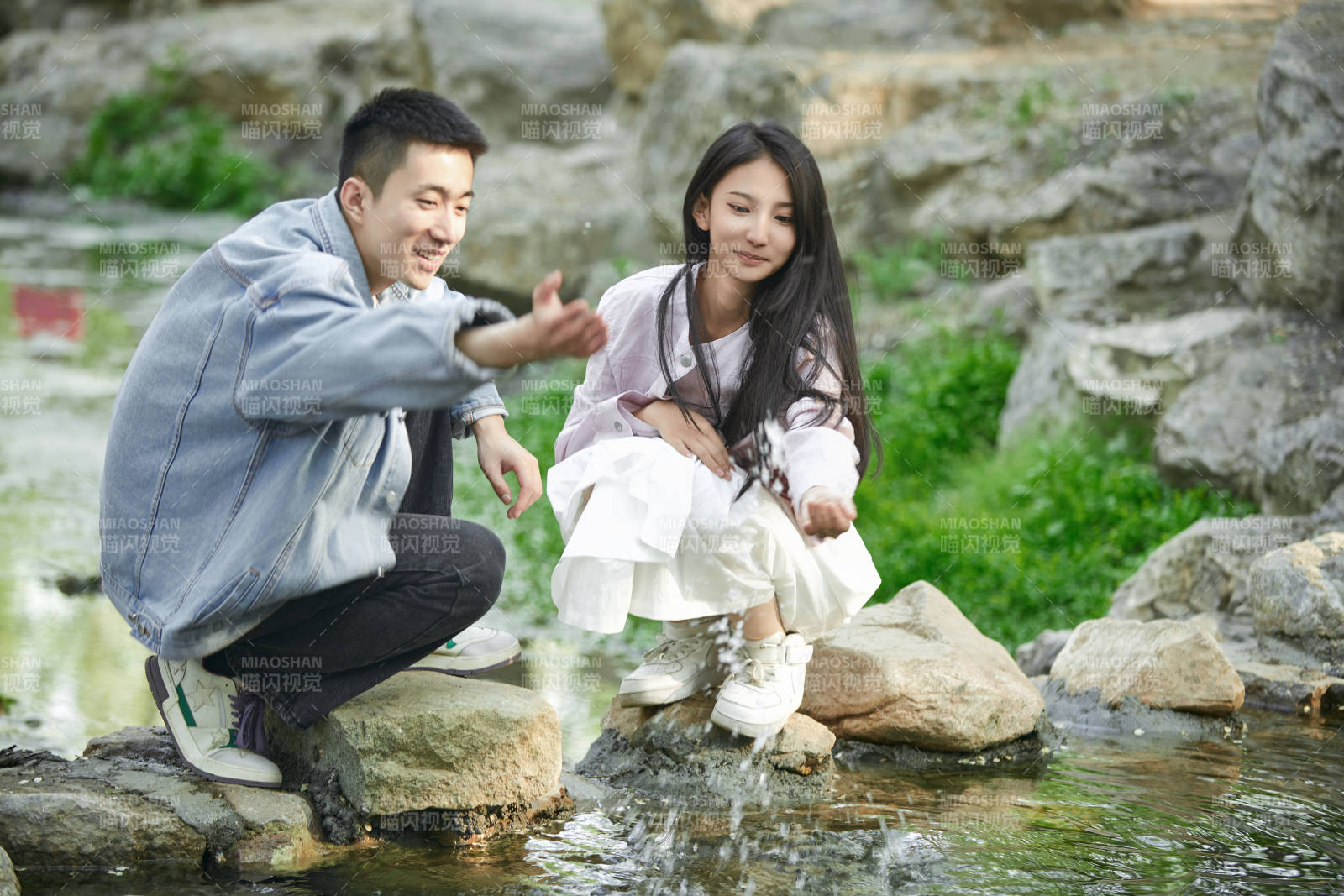 在公园小溪旁嬉戏玩水的青年情侣