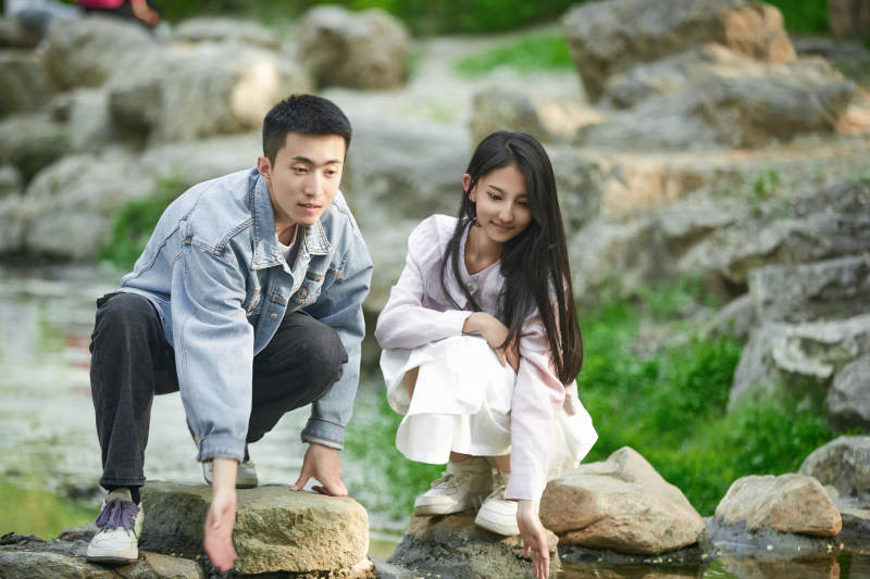 在公园小溪旁嬉戏玩水的青年情侣