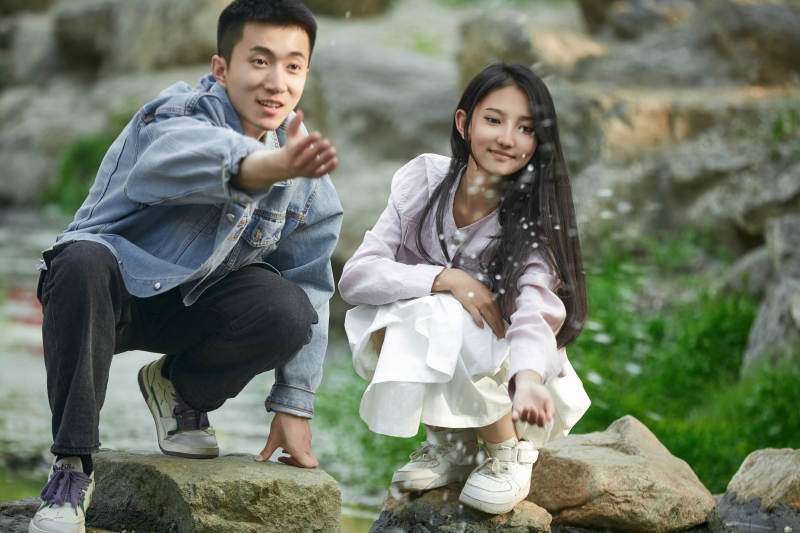 在公园小溪旁嬉戏玩水的青年情侣