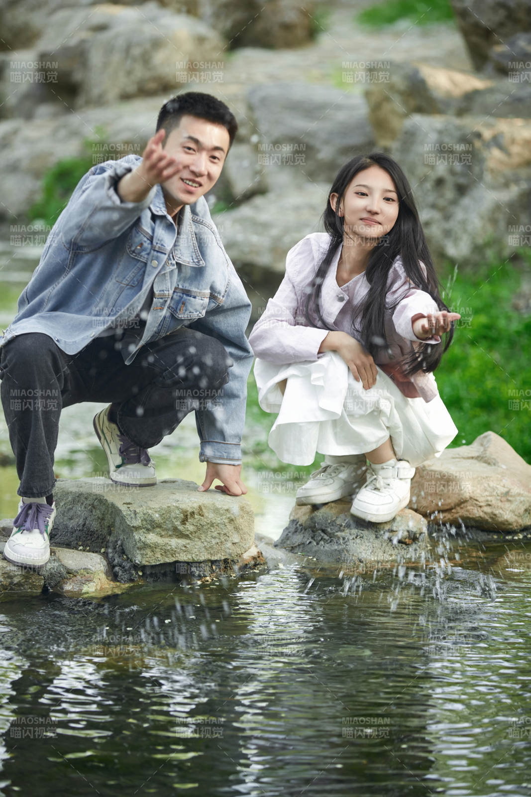 在公园小溪旁嬉戏玩水的青年情侣