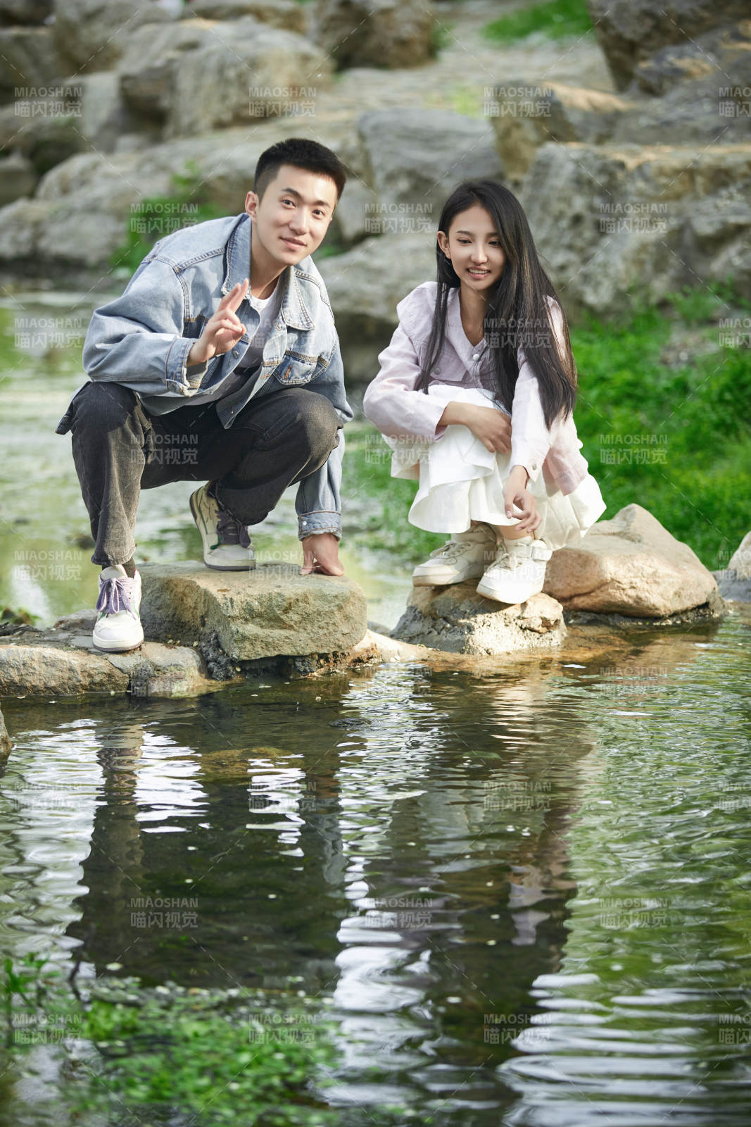 在公园小溪旁嬉戏玩水的青年情侣