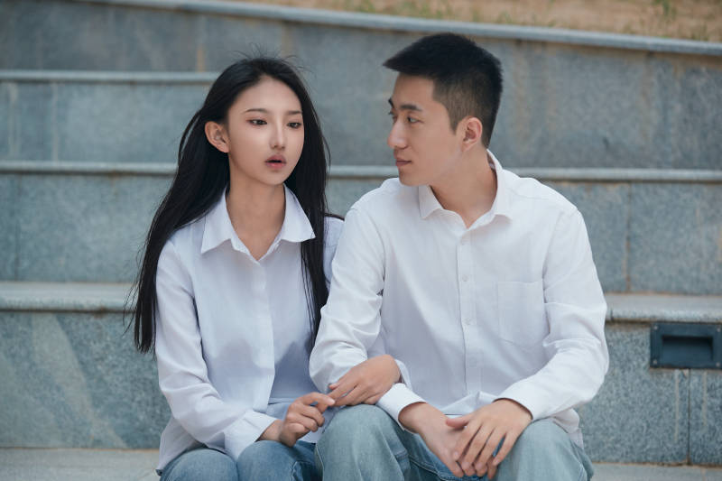 坐在户外台阶上的青年情侣