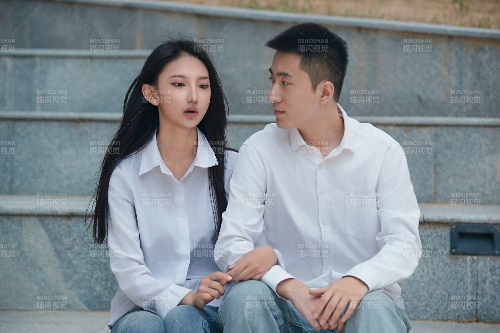 坐在户外台阶上的青年情侣