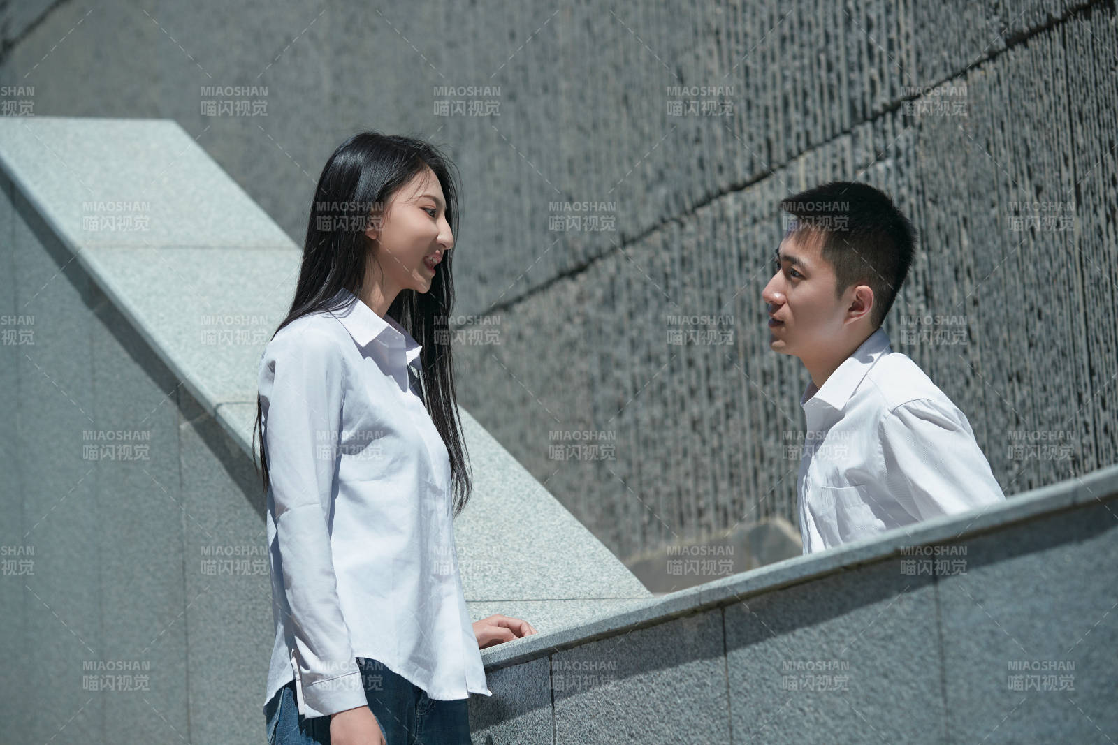 在户外台阶上对视的青年情侣