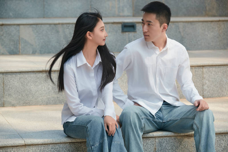 坐在户外台阶上的青年情侣