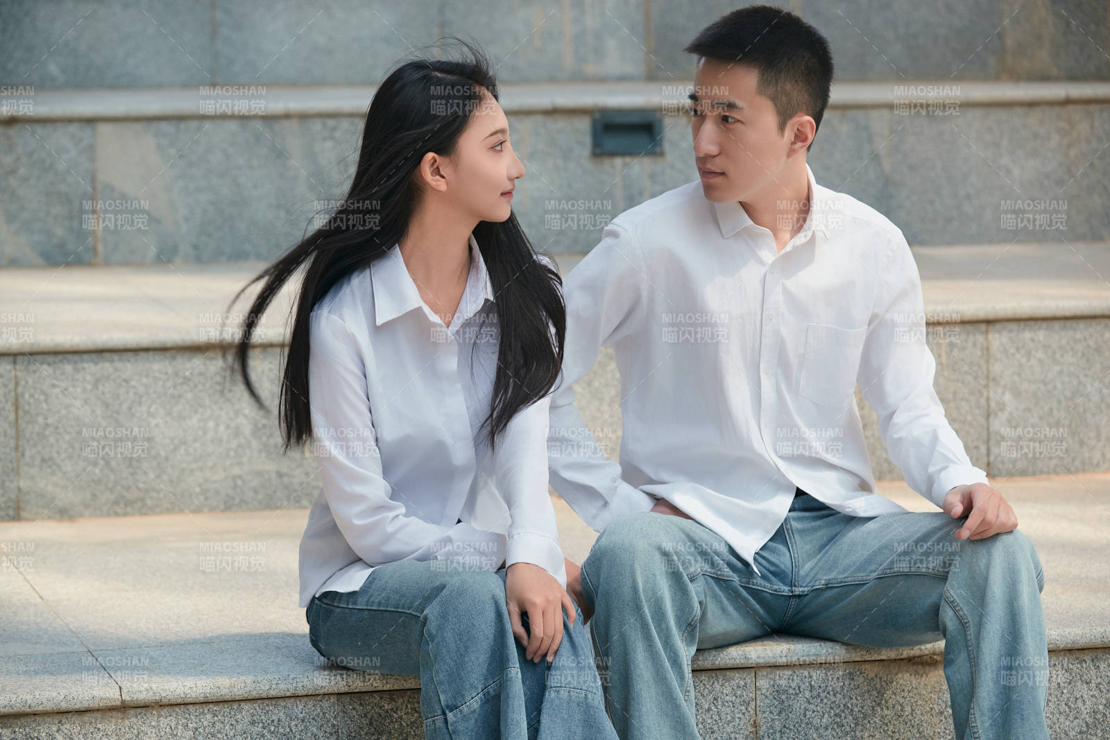 坐在户外台阶上的青年情侣