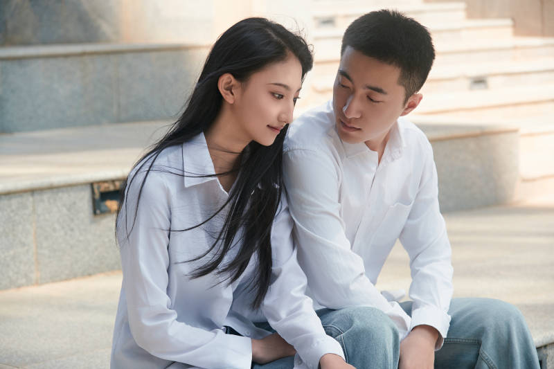 坐在户外台阶上的青年情侣