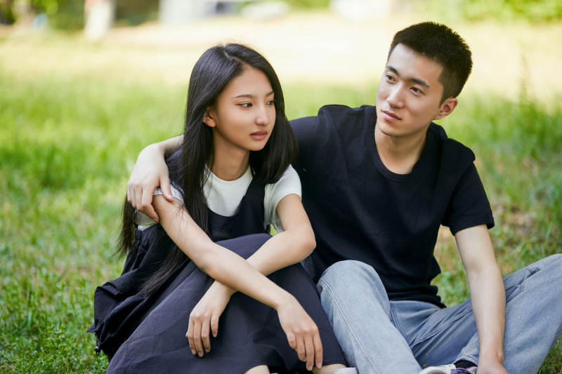 户外草坪上的恩爱年轻情侣