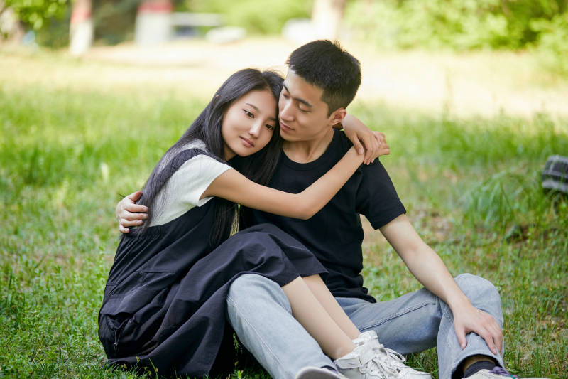 户外草坪上的恩爱年轻情侣