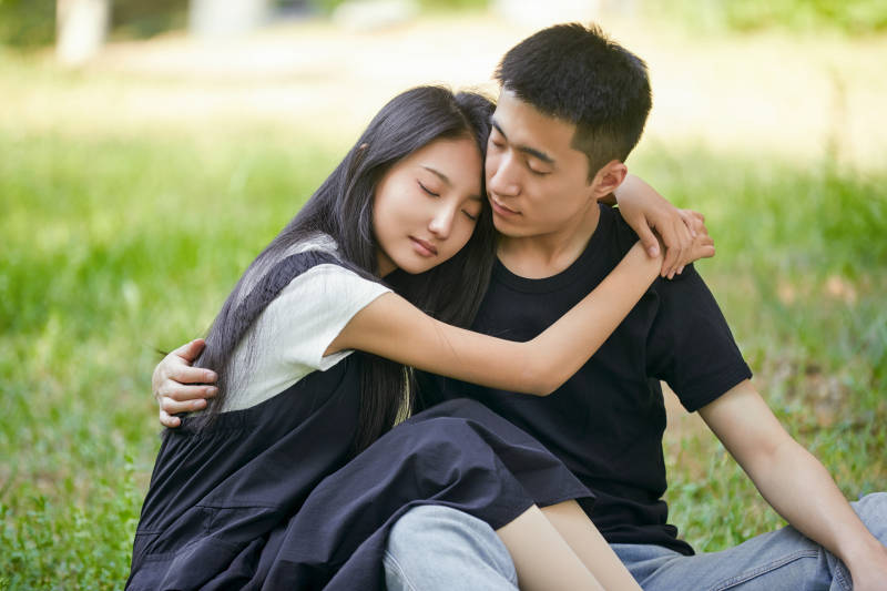 户外草坪上的恩爱年轻情侣