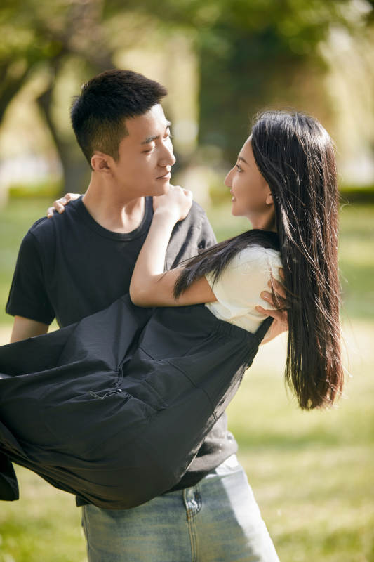 户外草坪上的恩爱年轻情侣