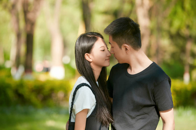 户外草坪上的恩爱年轻情侣