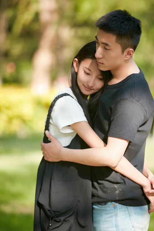 户外草坪上的恩爱年轻情侣