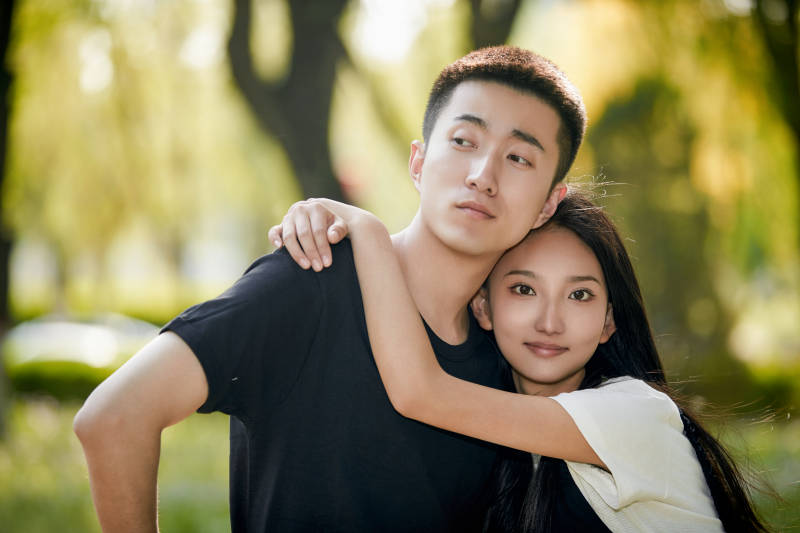 户外草坪上的恩爱年轻情侣