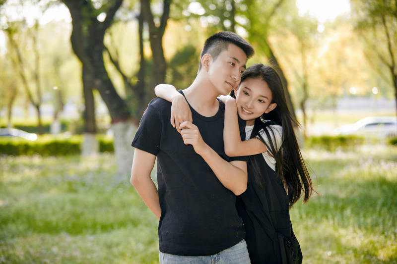 户外草坪上的恩爱年轻情侣